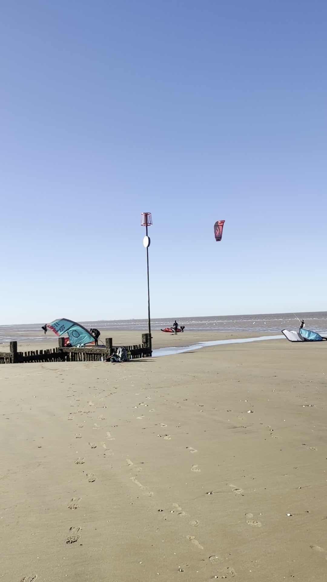 Red kite flying Hunstanton low tide beach North Norfolk UK watersports blue kite on sand